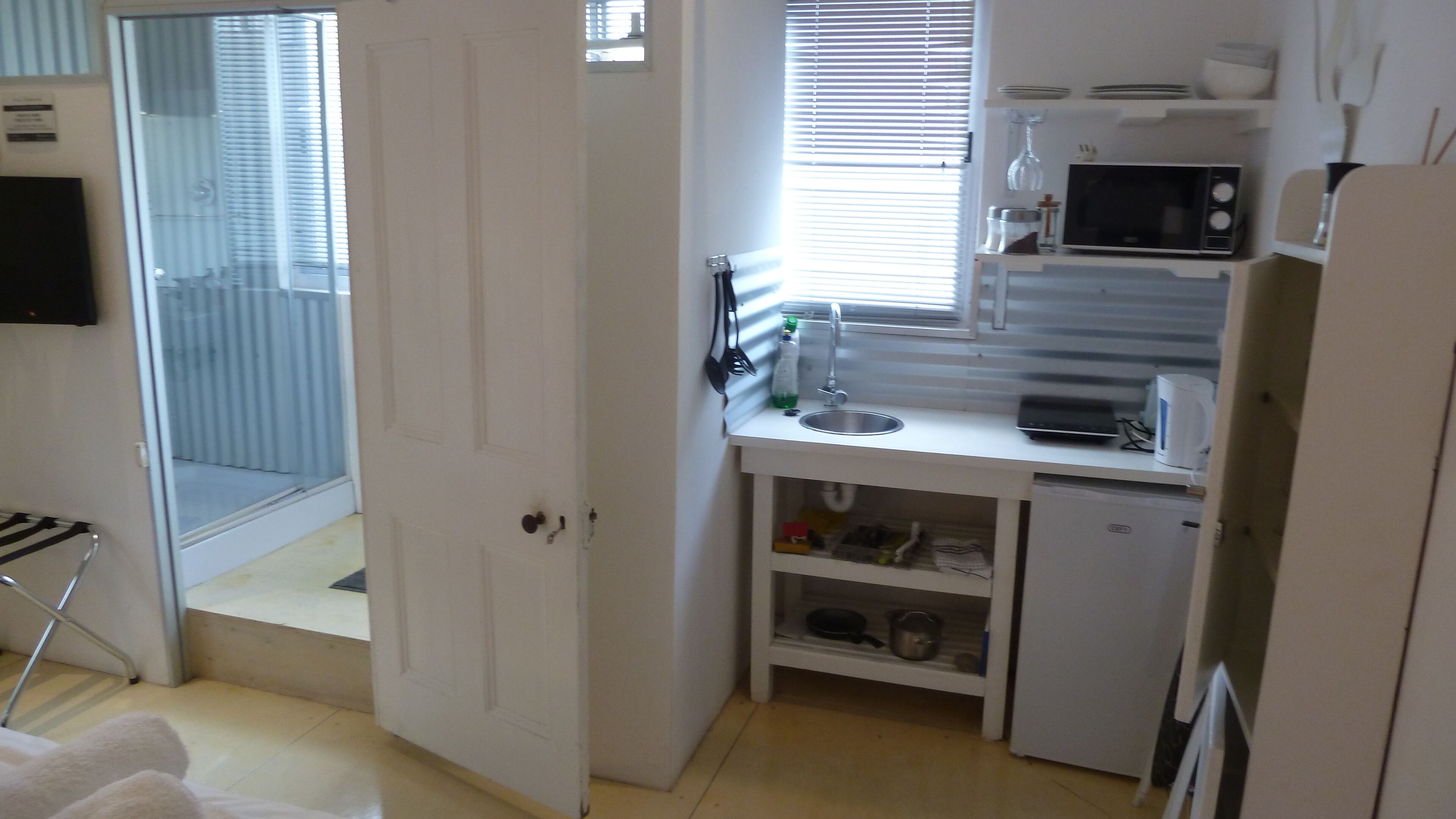 A compact kitchen with a microwave, sink, and storage cabinets.