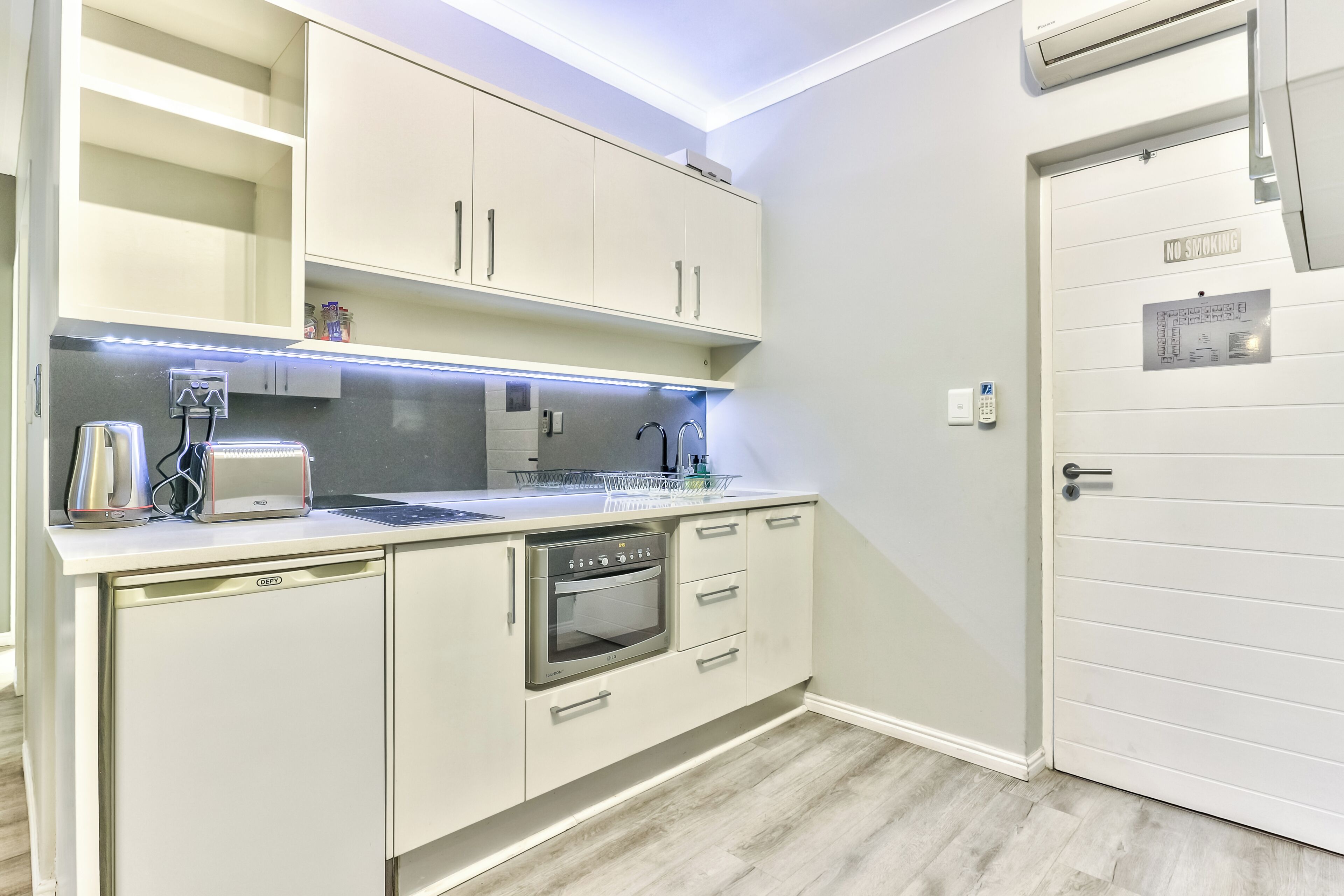 A compact kitchen with a built-in oven, a coffee machine, and a dishwasher.