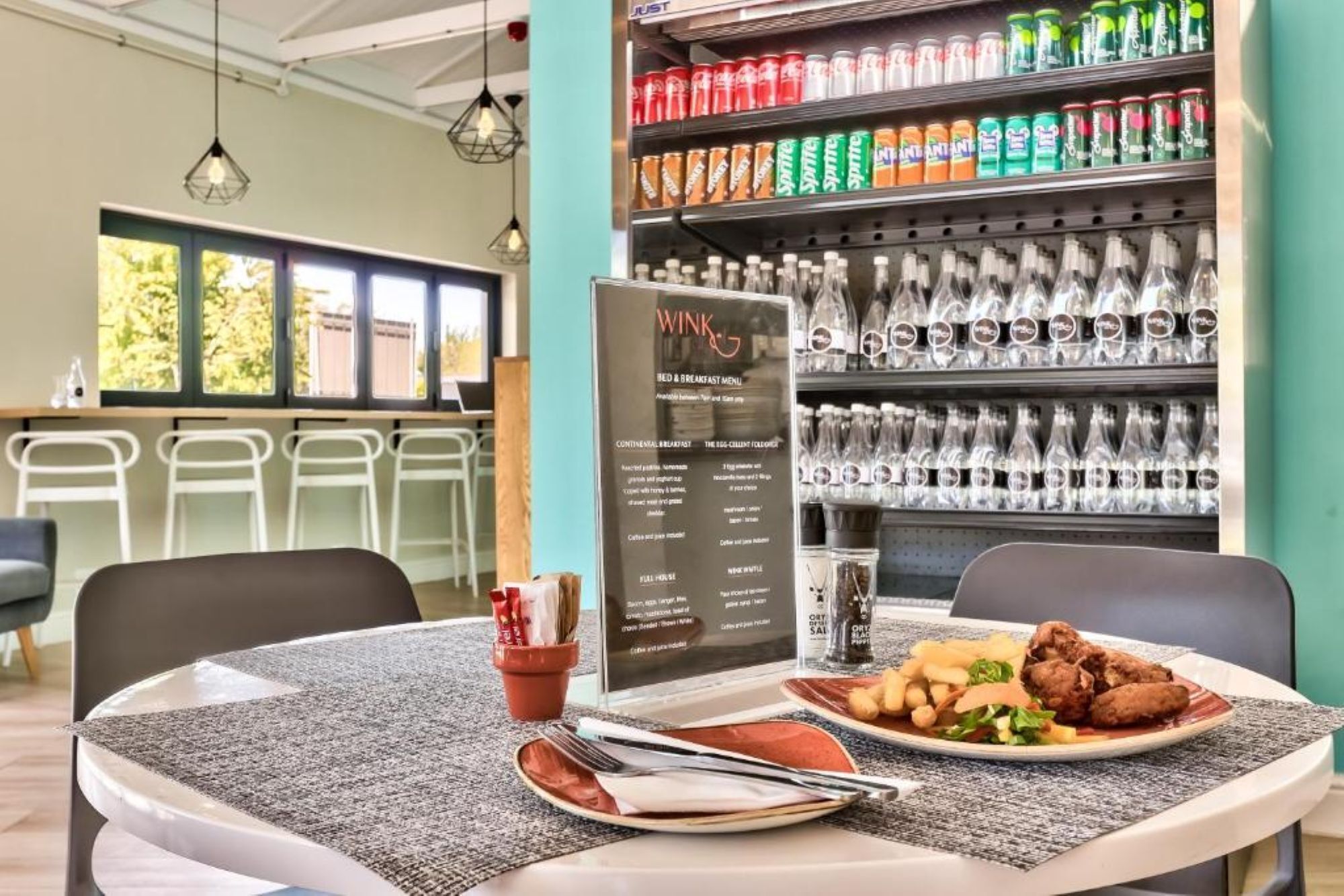 A restaurant with a menu board, a table with a meal, and a beverage shelf.