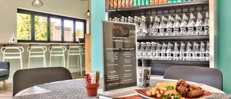 A restaurant with a menu board, a table with a meal, and a beverage shelf.
