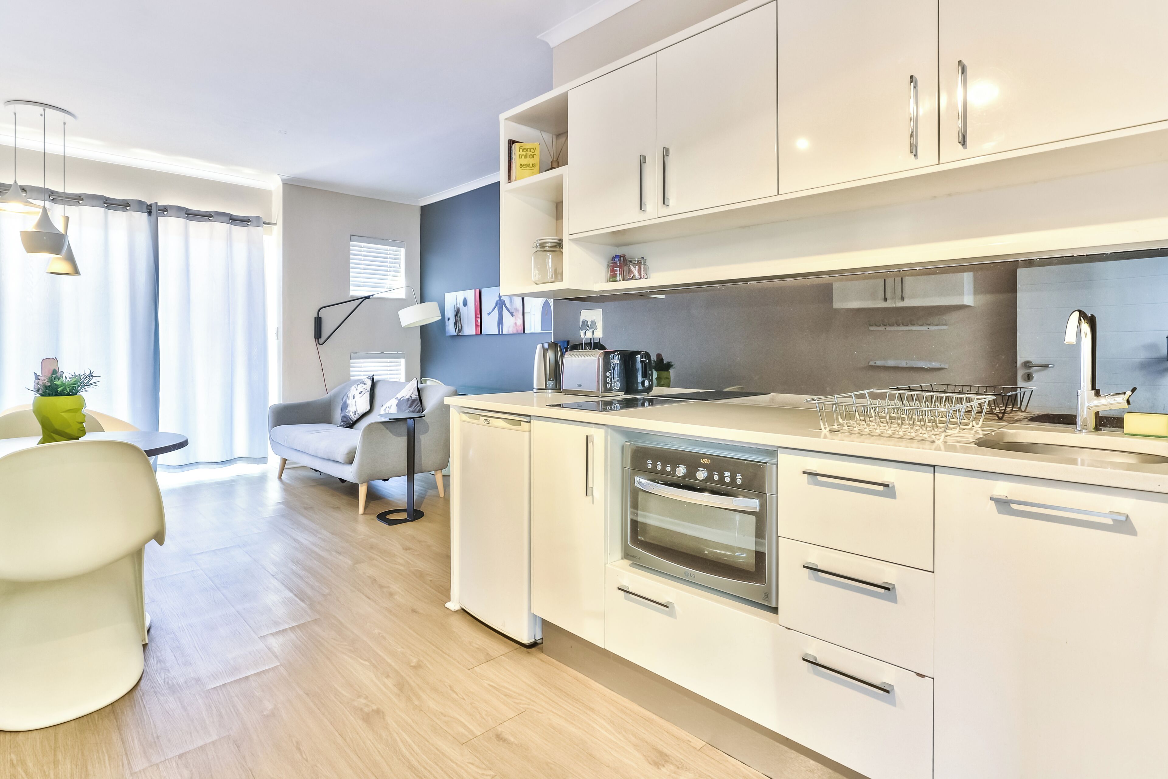 Een moderne keuken met witte kasten, een inbouwoven en een vaatwasser.
