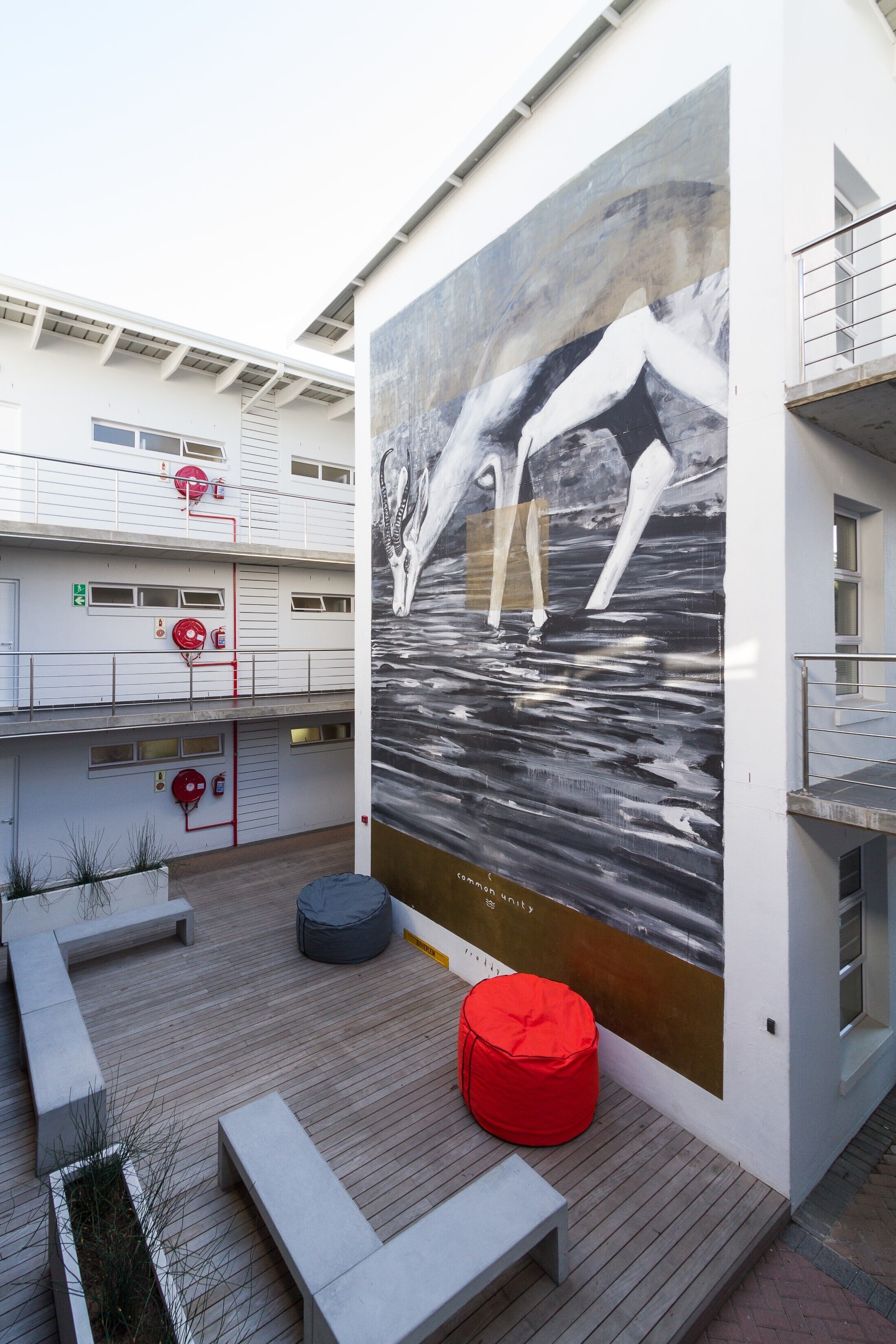 A modern outdoor area with a large mural of dolphins, seating, and a red fire extinguisher.
