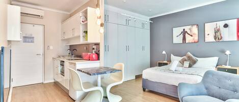 A compact living space with a kitchenette, a dining area, a bed, and a seating area.