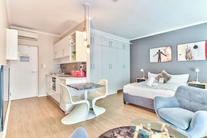 Un espacio habitable compacto con kitchenette, comedor, cama y zona de estar.