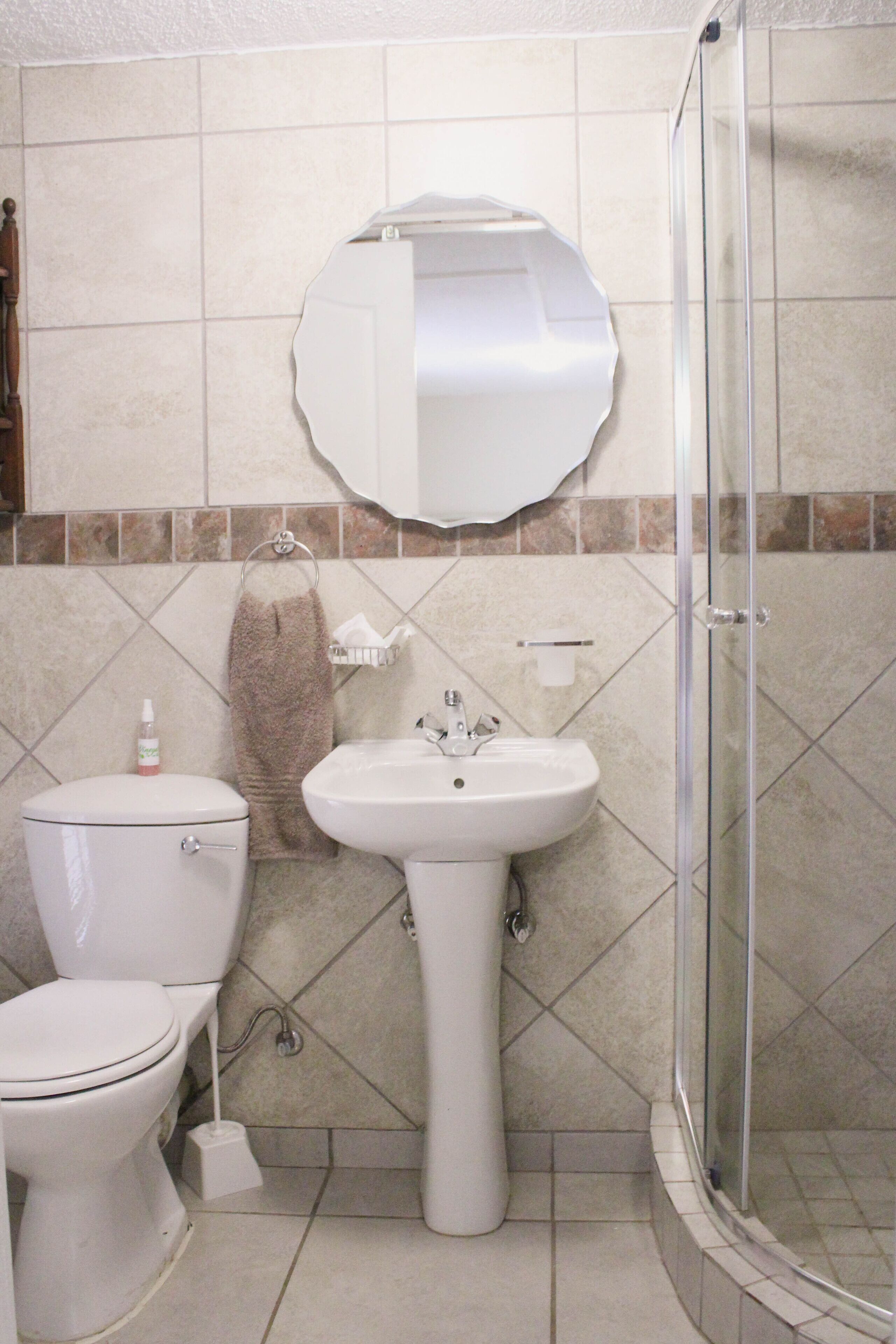 A bathroom with a toilet, sink, and glass shower enclosure.