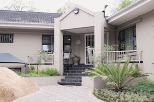 A modern house with a stone staircase leading to a front door, surrounded by a garden with various plants.