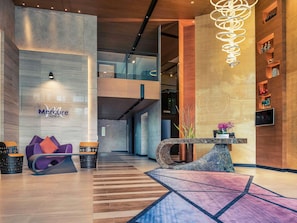 A modern hotel lobby with a reception desk, seating area, and a staircase leading to an upper level. - Mercure Bangkok Makkasan (Bangkok)