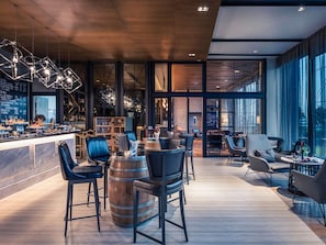 Un espace bar moderne avec des tabourets hauts, des tonneaux en bois et un comptoir.