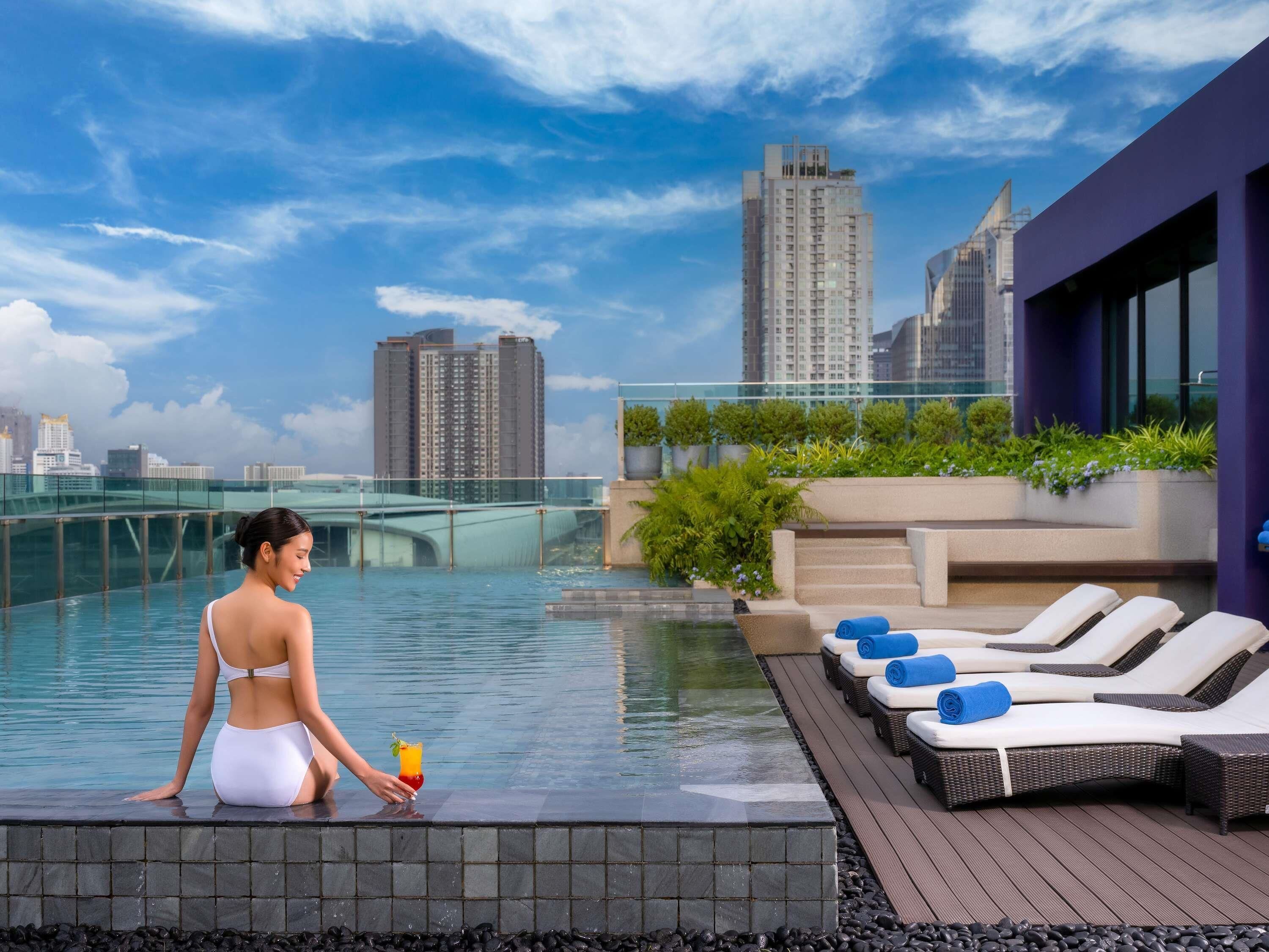 A rooftop pool with lounge chairs and a cityscape view.