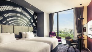 A hotel room with a large bed, a chair, a desk, and a city view. - Mercure Bangkok Makkasan (Bangkok)