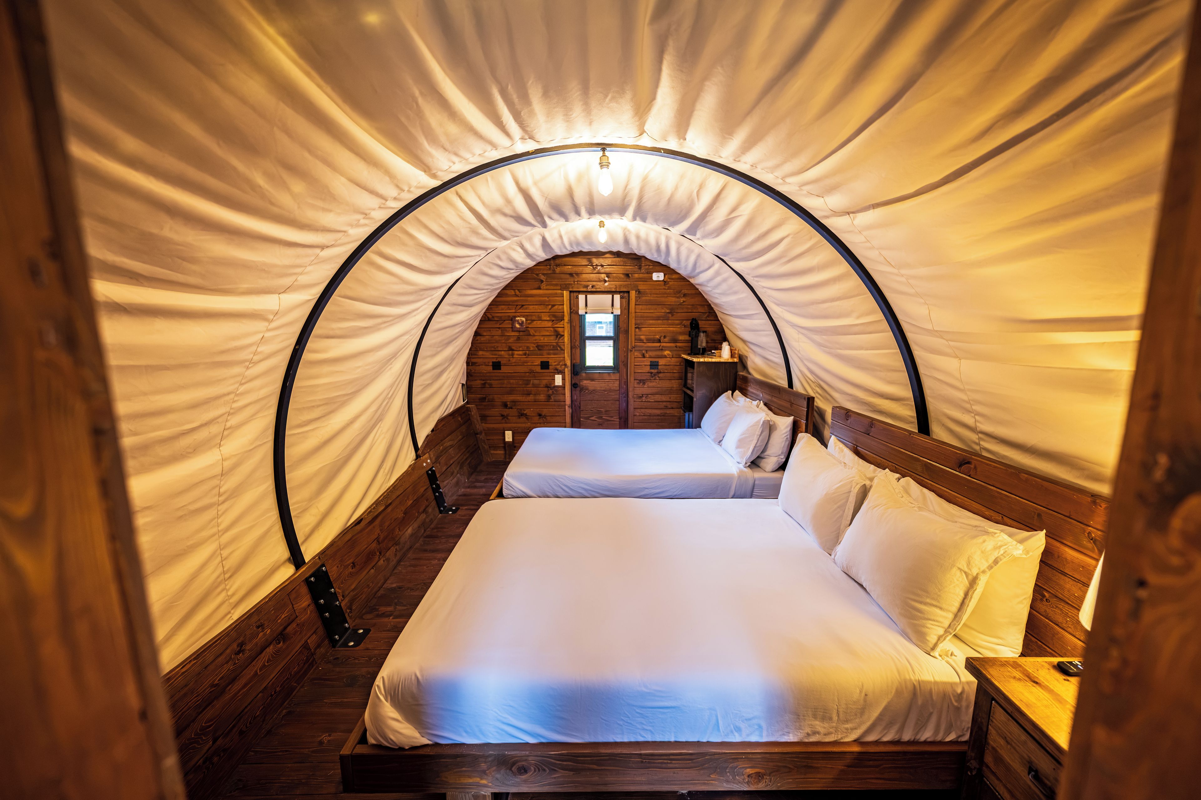 A tented room with a bed, wooden walls, and a door.