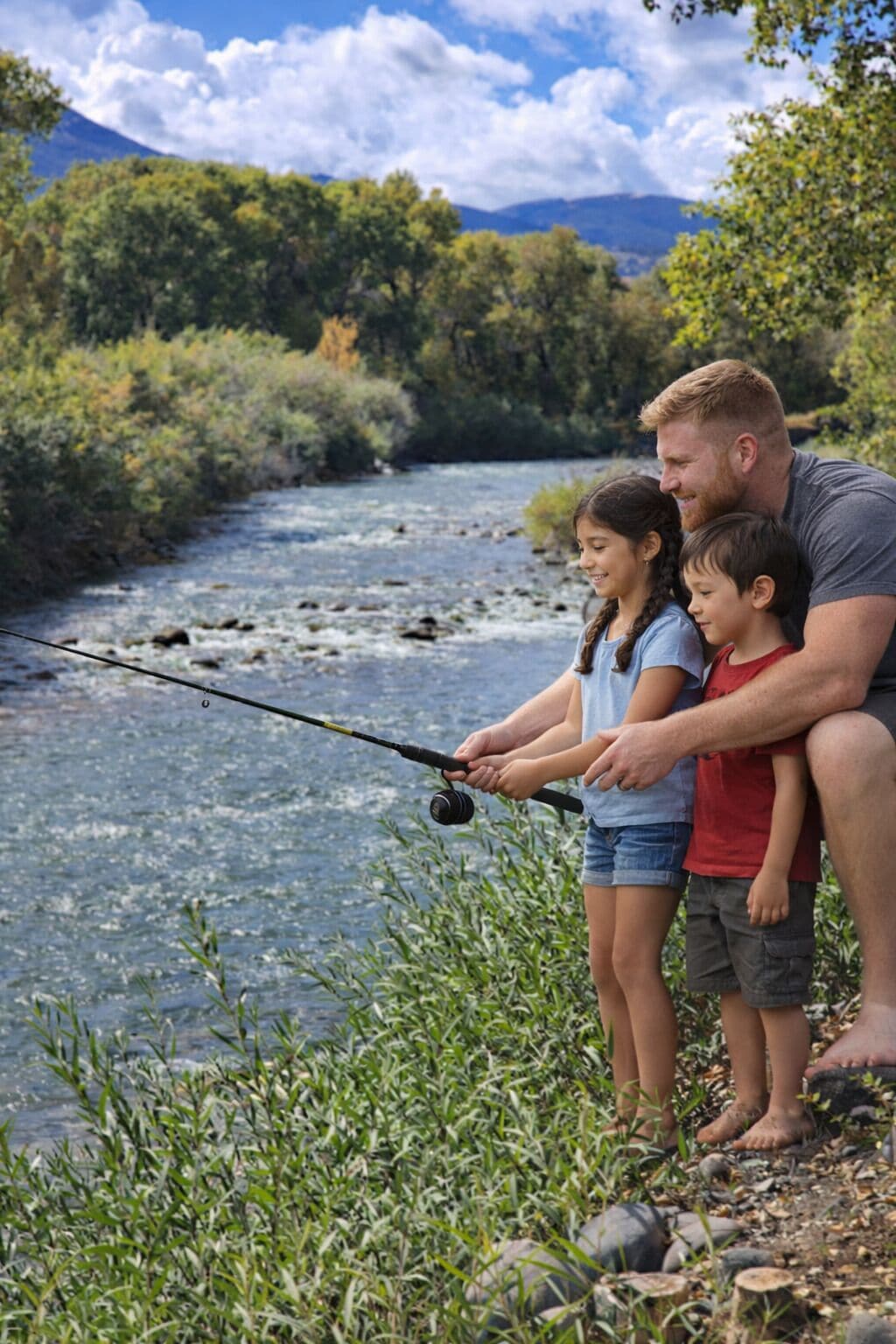 A family fishing by a river with a natural landscape in the background.