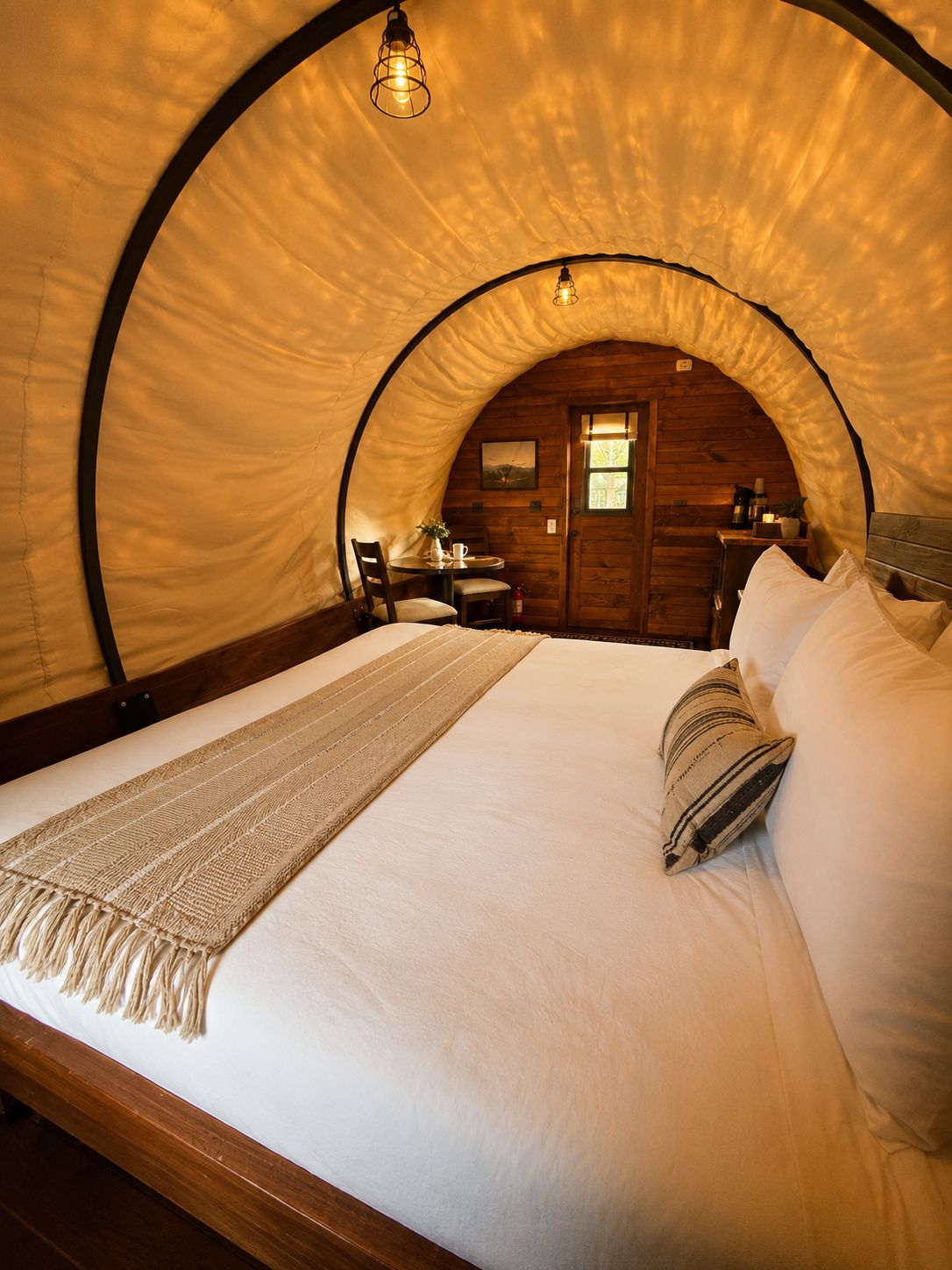 A cozy, arched room with a bed, a table, chairs, and a small window.