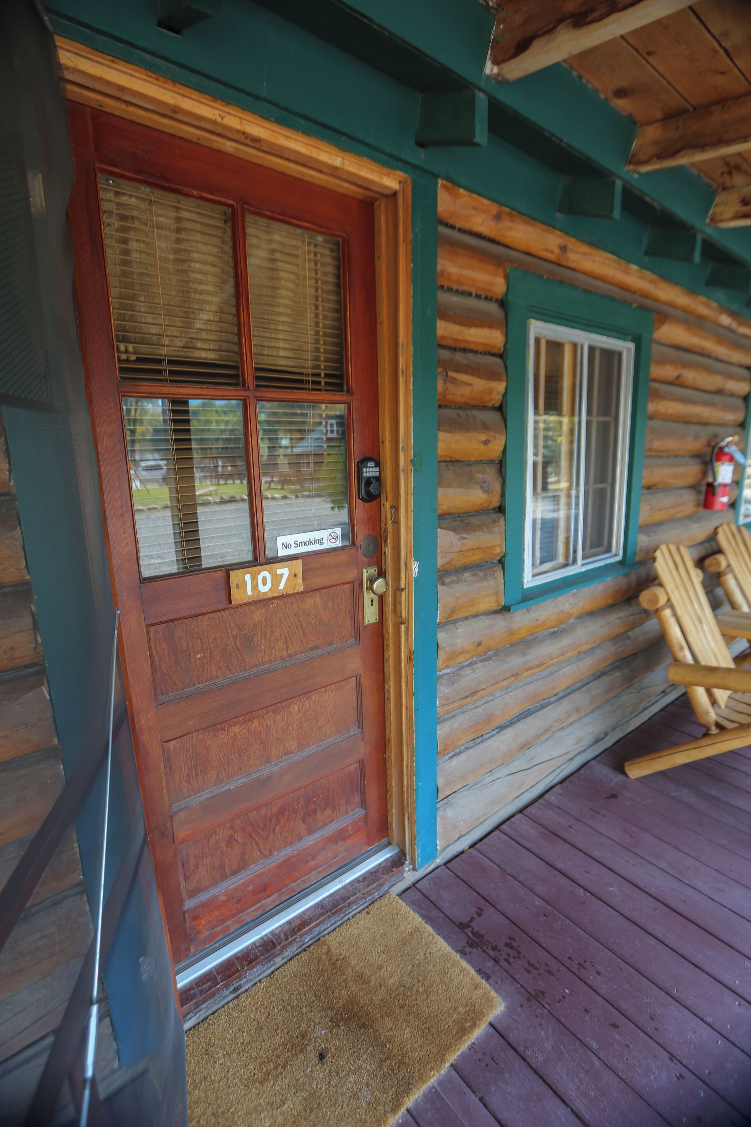 Une cabane en bois avec une porte portant le numéro « 107 » et un panneau indiquant « Il est interdit de fumer ».