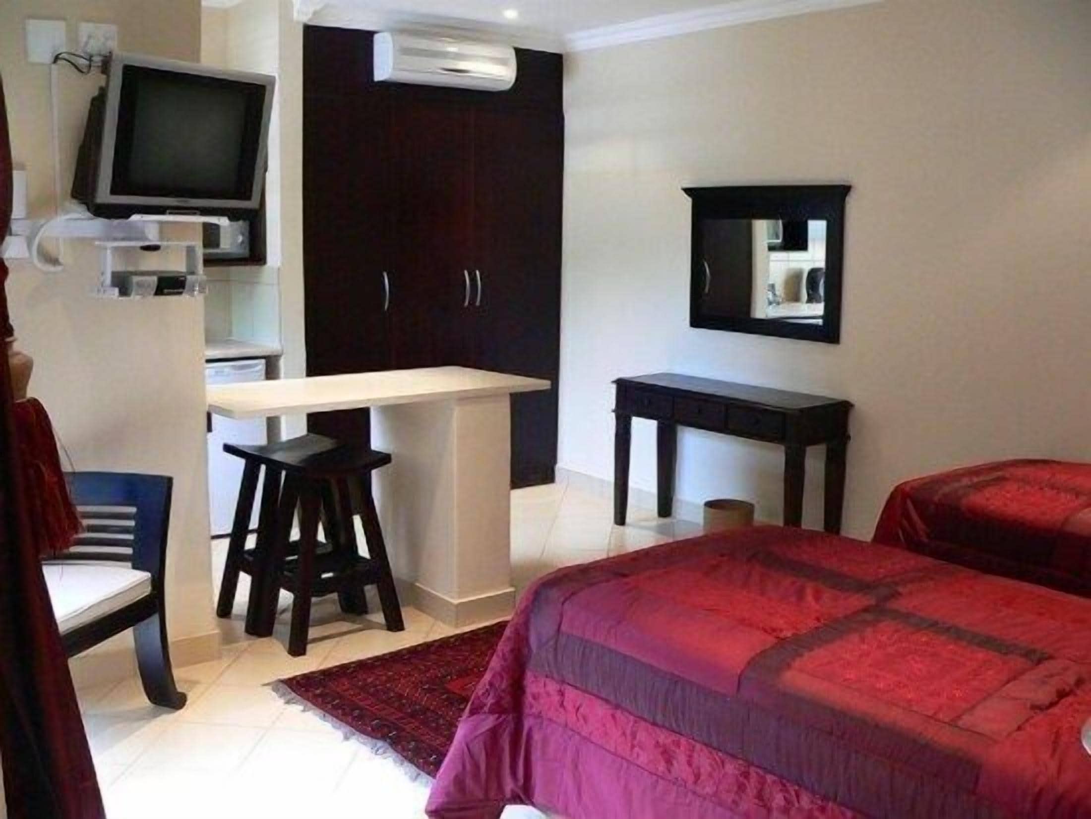 A bedroom with a bed, a desk, a chair, a TV, and a wardrobe.