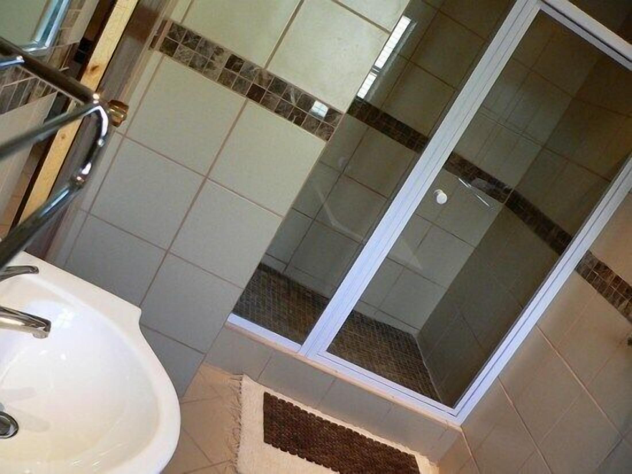 A bathroom with a white sink, a glass shower enclosure, and tiled walls.