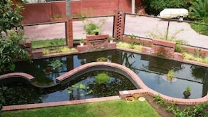 A small pond with a brick border and a grassy area in front. - Rustenburg Boutique Hotel (Rustenburg)