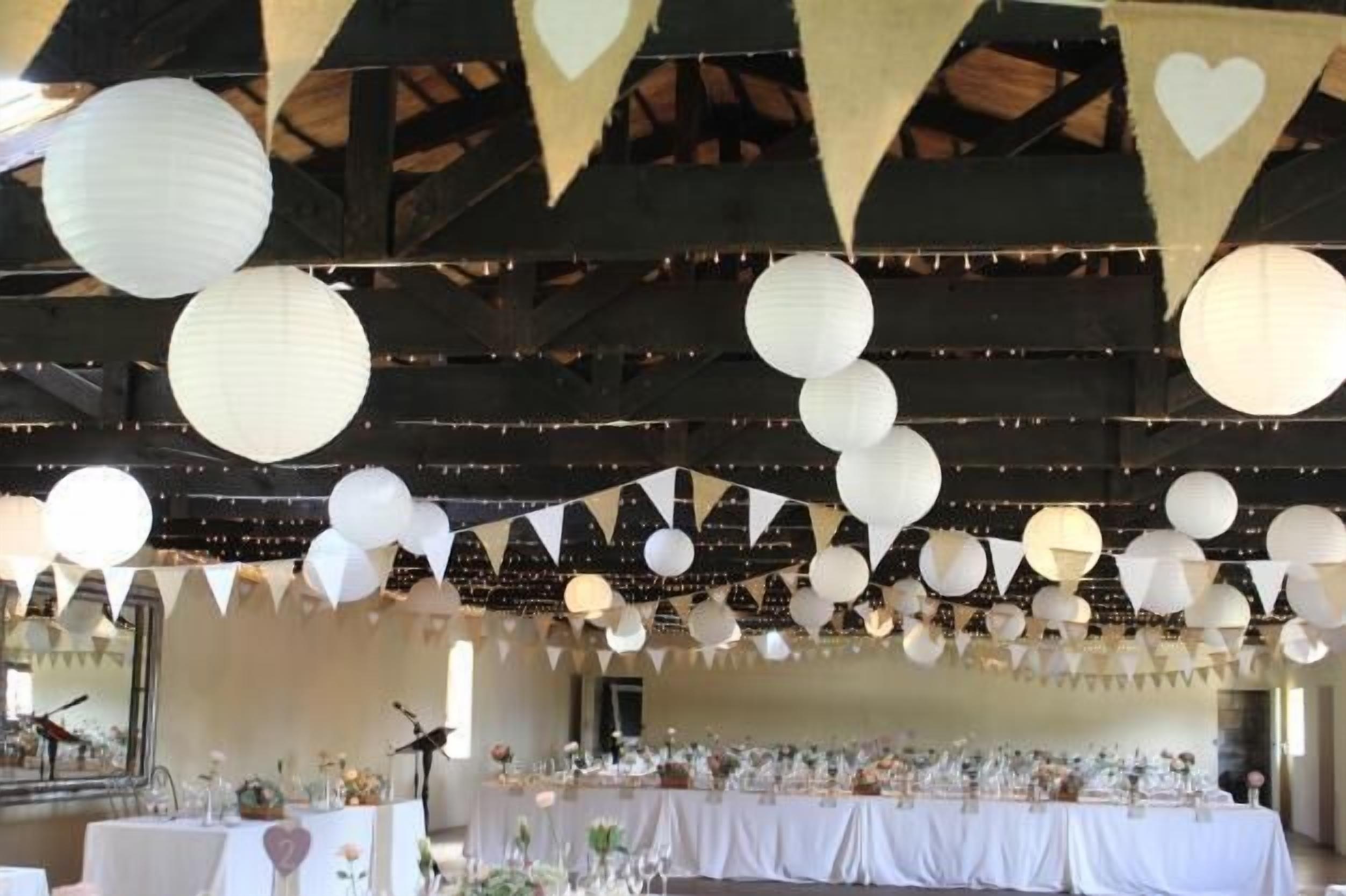 A banquet hall with tables set for a formal event, decorated with paper lanterns and bunting.