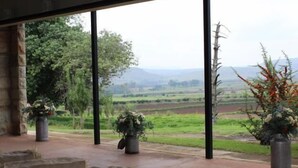 A room with large windows offering a view of a green landscape with trees and fields. - Oranje Gasteplaas Maloti Route (Fouriesburg)