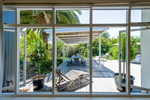 A covered outdoor deck with a table and chairs, surrounded by potted plants and a pergola. - Oude Berg Guesthouse (George)