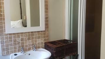 A bathroom with a white sink, a mirror, and a wicker basket on a black stand.