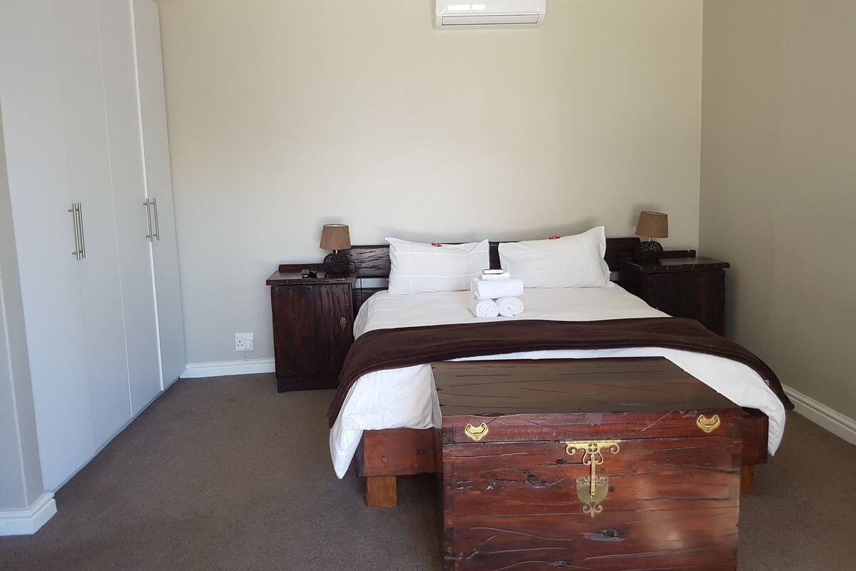 Um quarto com cama, mesas de cabeceira, guarda-roupa e cômoda.