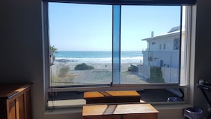 A room with a large window overlooking a beach and ocean. - Melkbosch Guesthouse (Cape Town)