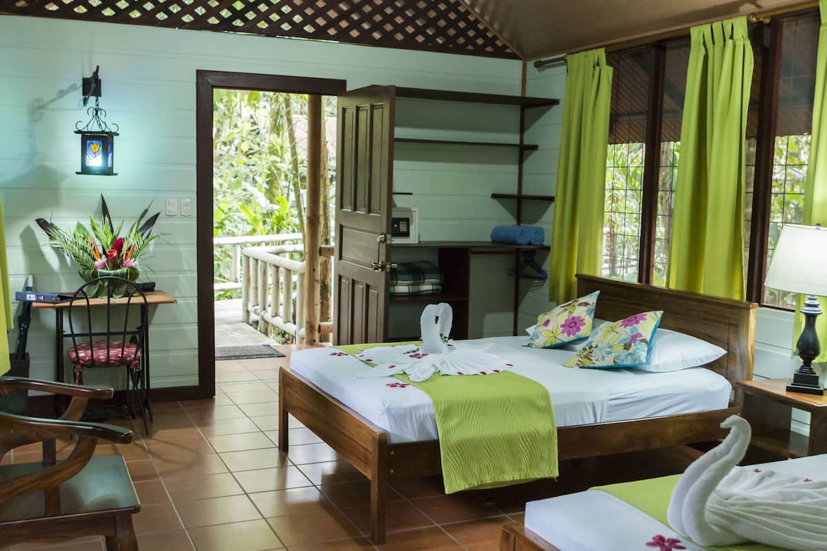 A room with a bed, a desk, a chair, a lamp, and a view of the outdoors.