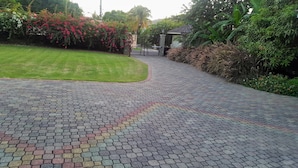 A paved pathway leading to a gated entrance surrounded by lush greenery and flowering plants. - The Inn at 6 (Kingston)