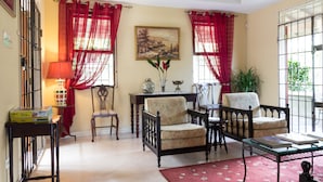 A living room with two armchairs, a table, a lamp, and a painting on the wall. - The Inn at 6 (Kingston)