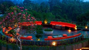 A circular outdoor seating area with red cushions, surrounded by lush greenery and a view of a forested hill. - Sthala, A Tribute Portfolio Hotel, Ubud Bali (Ubud)