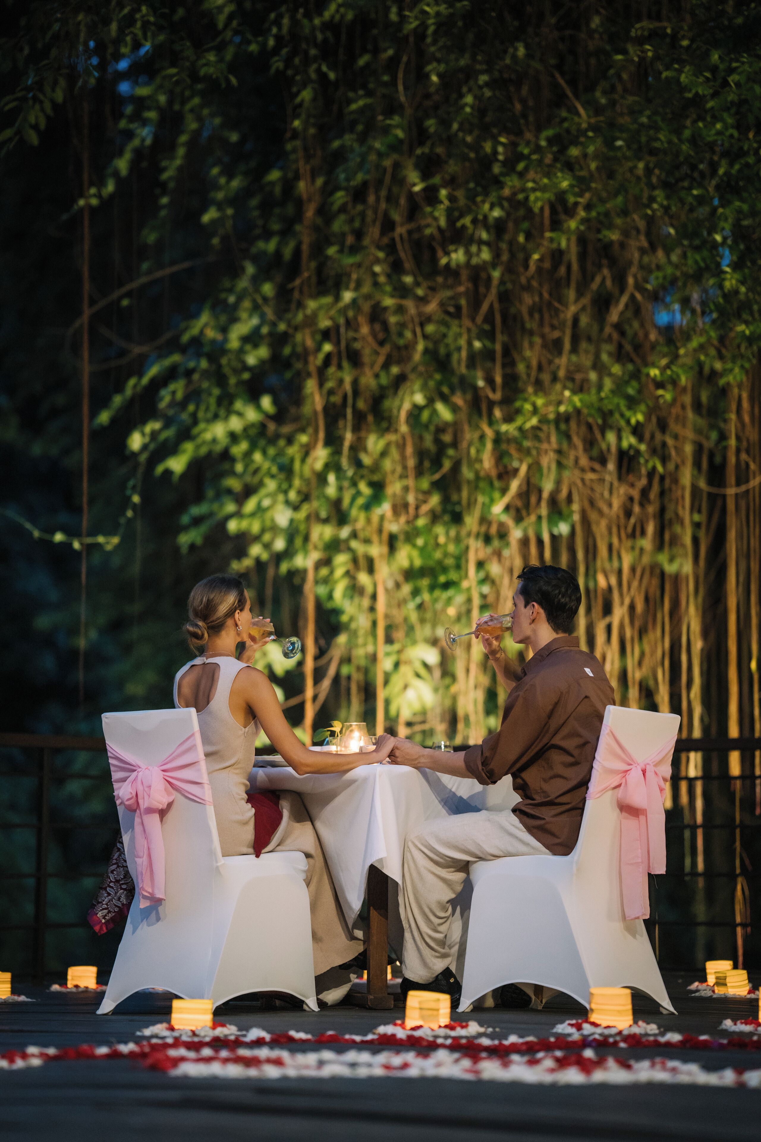 Una pareja cenando en una mesa al aire libre con un bosque de fondo.