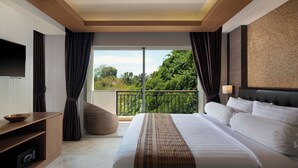 A modern hotel room with a large bed, a flat-screen TV, a wooden cabinet, and a balcony with a view of greenery.