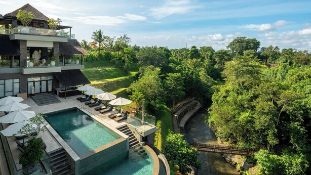 A modern resort with a pool, outdoor seating, and a lush garden view.