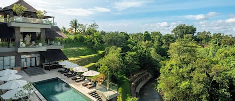 A modern resort with a pool, outdoor seating, and a lush garden view.