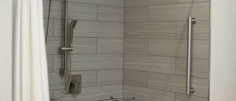 A shower area with a grab bar, a towel rack, and a showerhead.
