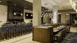 Een moderne hotel lobby met een bar, zithoekjes en een grote spiegel.
