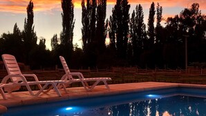 Una piscina con sillas de descanso y vista al atardecer.