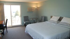 Ein Hotelzimmer mit einem Bett, zwei Sesseln, einem kleinen Tisch und einer Schiebetür zu einem Außenbereich.