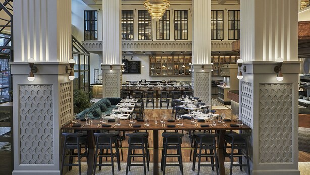 Un comedor amplio con techos altos, grandes candelabros y un diseño de interiores moderno.