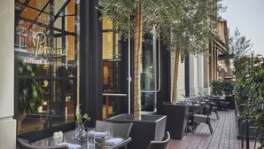 Un área de comedor al aire libre con mobiliario de mimbre y plantas en macetas.