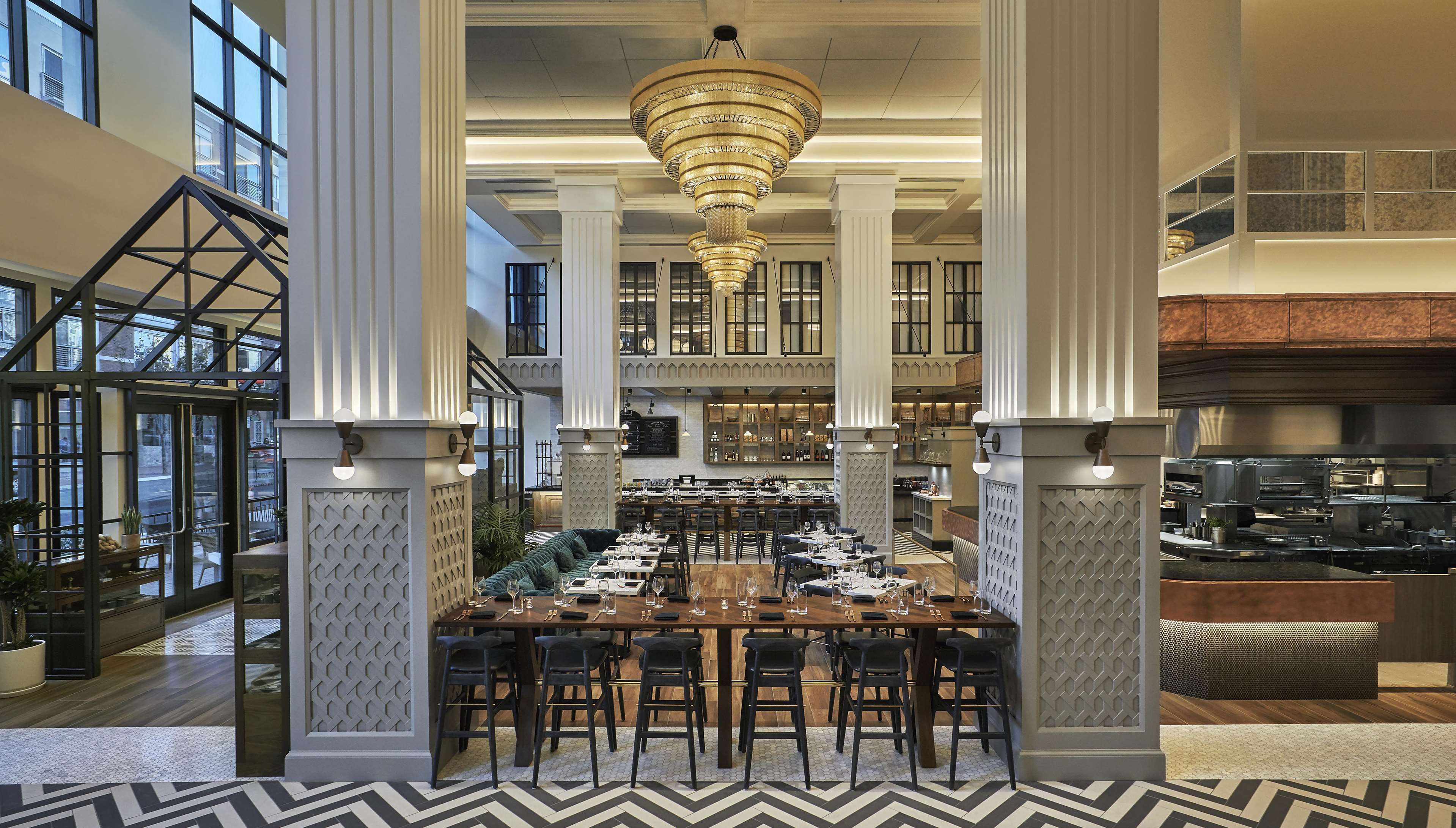 A spacious dining area with high ceilings, large windows, and a central chandelier.