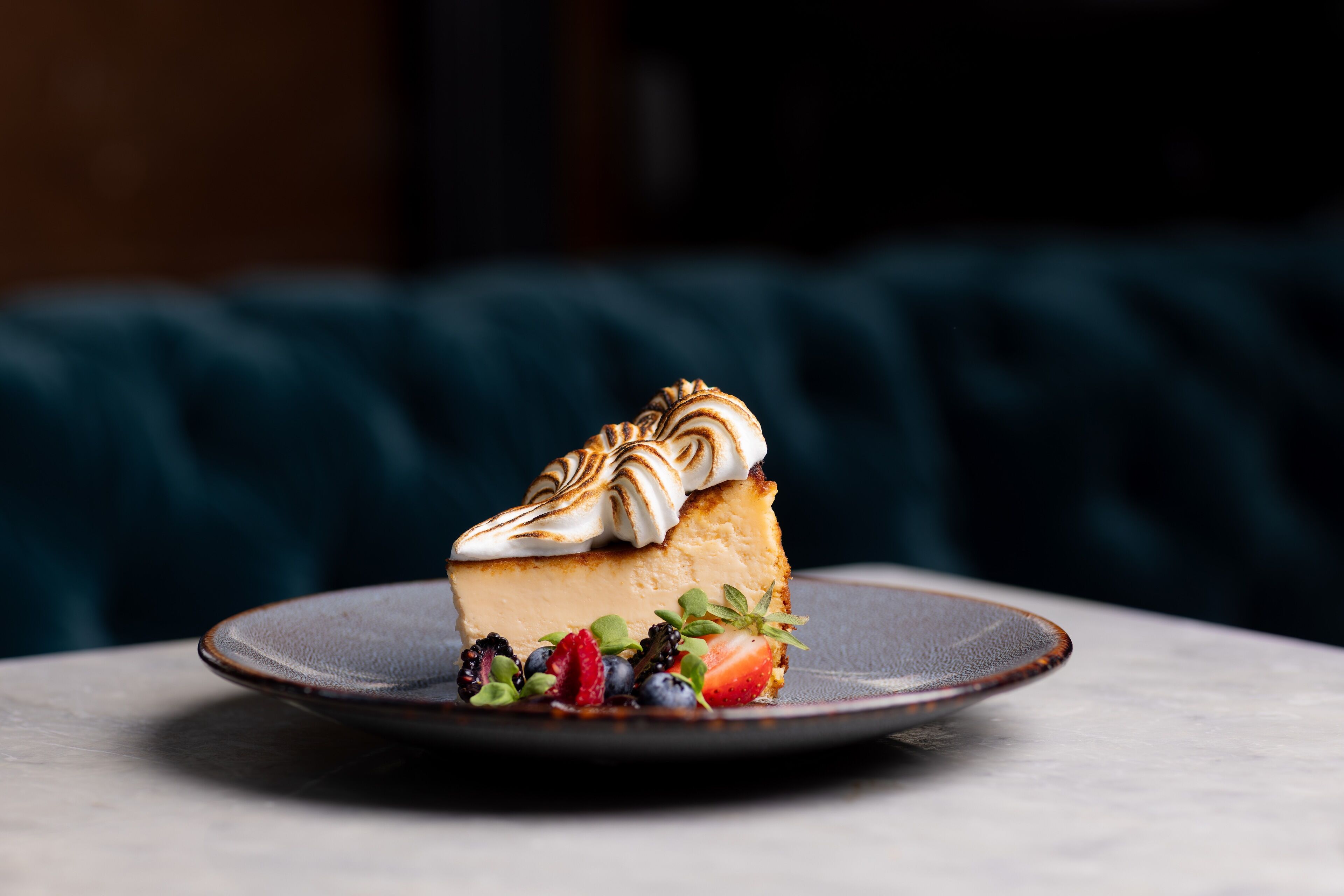 A slice of cheesecake on a plate with fruit garnish.