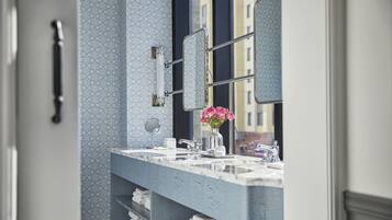 A bathroom with a marble vanity, a large mirror, and a vase with flowers.