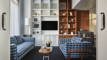A living room with two blue plaid sofas, a wooden coffee table, and a TV wall unit with shelves.