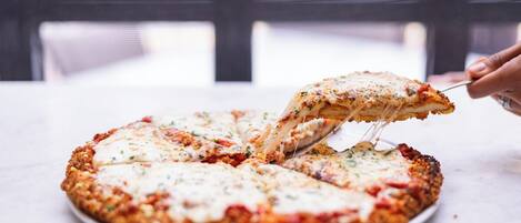 Una pizza con una porción levantada, sobre un plato blanco.