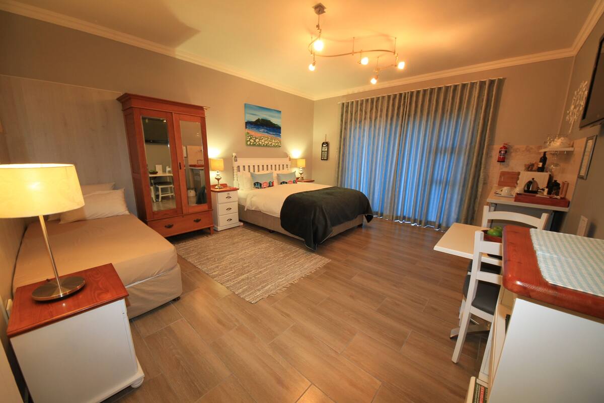 A hotel room with a bed, bedside tables, a wardrobe, a desk, and a chair.