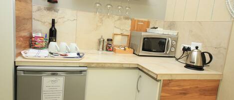 A compact kitchen with a microwave, coffee maker, and a small refrigerator.