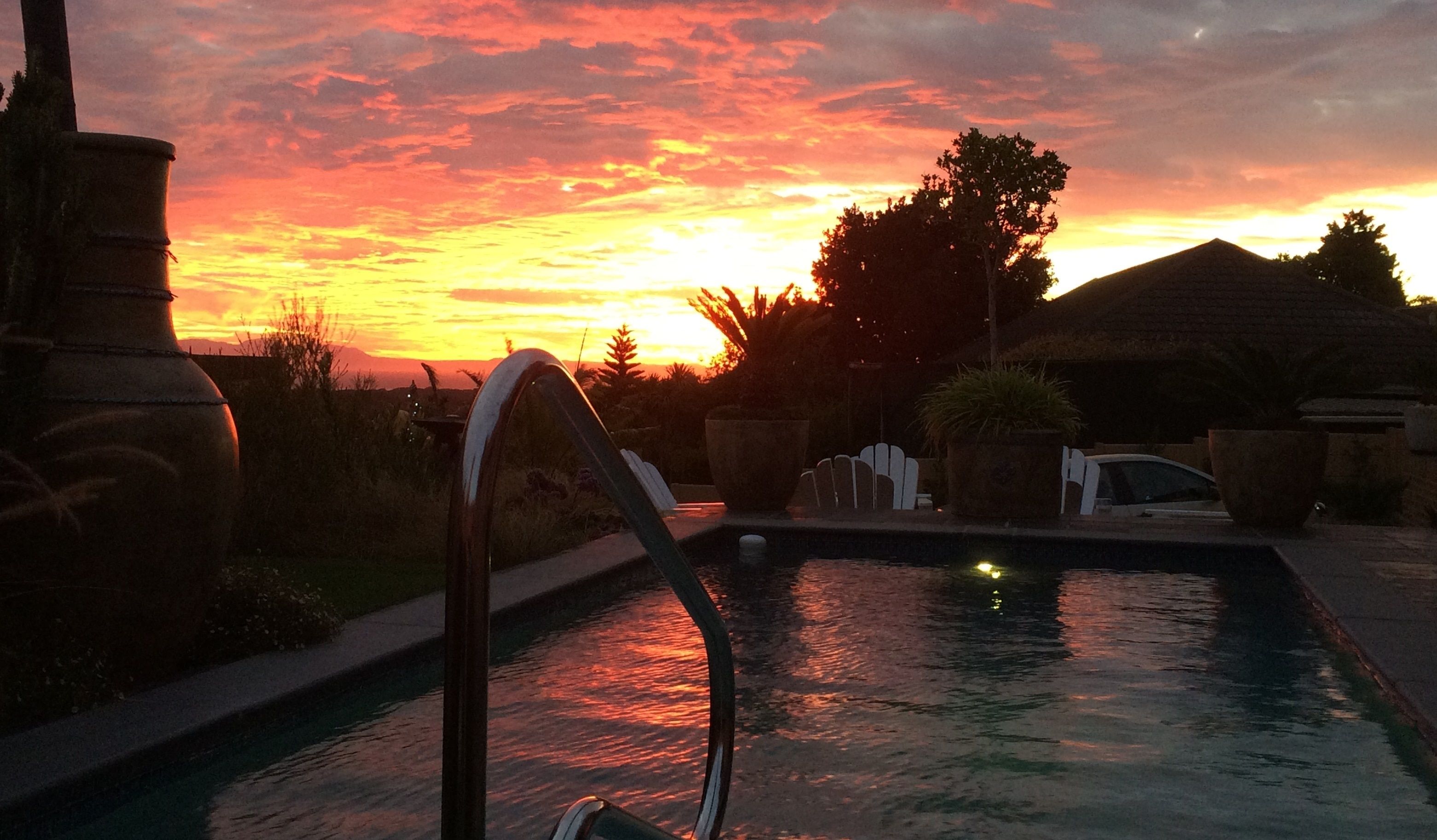 A swimming pool with a sunset in the background.