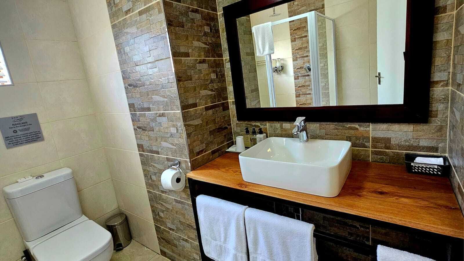 A bathroom with a white sink, a mirror, and a toilet.